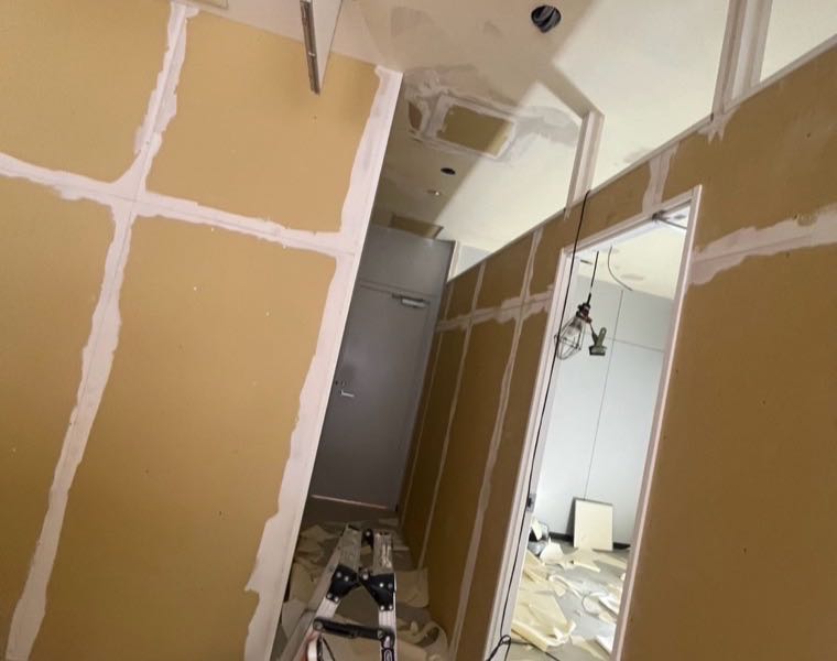 施工前：下地ボードの継ぎ目をパテで処理した通路と、開口部の枠まわり